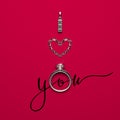 An engagement ring, a white gold pendant and several diamonds set in the shape of a heart on a red background with a calligraphic