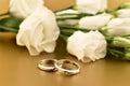 Two golden wedding rings with white roses on a gold background stock images Royalty Free Stock Photo