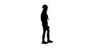Engeneer girl in a helmet and with headphones on her neck goes . Silhouette. White background . Side view