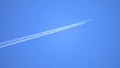 Engine exhaust contrails forming behind flying commercial airplane