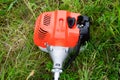 The engine of a gas trimmer lies on the grass. Power part of the trimmer