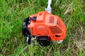 The engine of a gas trimmer lies on the grass. Power part of the trimmer