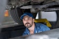 An engine mechanic inspecting the car in Auto Car Service. Car mechanics repairing in a car on hydraulic lift Royalty Free Stock Photo