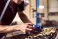 Engine oil changing in auto workshop. Focus on pouring grease from bottle by repairman hands. Maintenance car engine