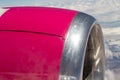 Bright pink Engine of passenger airplane - sideview close up with clouds in background