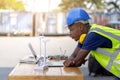 Engineer African American black worker discussing of solar energy from wind turbine model and online with laptop at construction