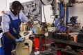 Engineer afro american man in coveralls checking motorcycle in workshop Royalty Free Stock Photo