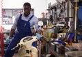 Engineer afro american man in coveralls checking motorcycle in workshop Royalty Free Stock Photo