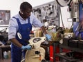 Engineer afro american man in coveralls checking motorcycle in workshop Royalty Free Stock Photo