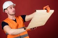 Engineer, architect, builder on strict face holds old blueprint in hands, supervises construction site. Man in helmet Royalty Free Stock Photo