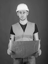 Engineer, architect, labourer, builder on strict face holds old blueprint in hands. Man, handyman in helmet, hard hat Royalty Free Stock Photo