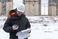 Engineer or Architect with protective safety helmet checking architectural drawing calling support team at construction