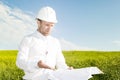 Engineer builder is dissatisfied with poor project documentation. Worker with blueprints on background of meadow Royalty Free Stock Photo