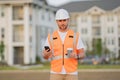 Engineer builder drinking take away coffee using phone on break. Builder at construction site. Buider with helmet on Royalty Free Stock Photo