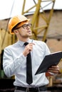 Engineer builder in a helmet holds folder at construction site Royalty Free Stock Photo