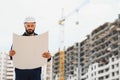 Engineer builder wearing safety vest with blueprint at construction site Royalty Free Stock Photo