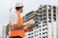 Engineer builder wearing safety vest with blueprint at construction site