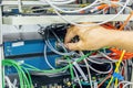 Engineer connecting network cable to switch of fiber optic hub for digital communications in server room Royalty Free Stock Photo