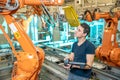 Engineer controls using remote control of industrial robot in factory. Automatic welding and gluing using automation and