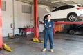 Engineer In Coveralls Standing Arms Crossed Against Car Lift