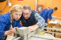 Engineer cutting sheet metal with apprentice