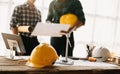 Engineer desk with object paper and tablet with blurry engineer teamwork hardworking to consults about their building project