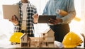 Engineer desk with object paper and tablet with blurry engineer teamwork hardworking to consults about their building project