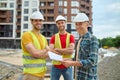 Engineer with drawing and two workers at construction site Royalty Free Stock Photo