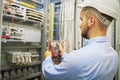 Engineer electric with multimeter. Side view of male technician examining fusebox with multimeter probe. Royalty Free Stock Photo