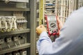 Engineer electrician with multimeter in hands at electric automation box panel. Service engineer tests circuit of industrial