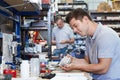 Engineer In Factory Measuring Component At Work Bench Using Micrometer