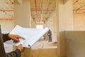 Engineer finger point on paper plan blueprint in check building technician place construction site wall interior with copy space