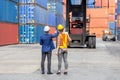 Engineer and foreman team in hardhat and safety vest control loading containers box from cargo, Logistic concept Royalty Free Stock Photo