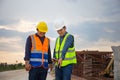 Engineer and foreman worker checking project at building site, Engineer and builders in hardhats discussing blueprint on Royalty Free Stock Photo