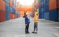 Engineer and foreman worker team in hardhat and safety vest control loading containers box from cargo Royalty Free Stock Photo