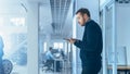 Engineer with Glasses and Beard Enters a High Tech Development Facility Holding a Tablet Computer. Royalty Free Stock Photo