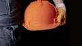 An engineer or handyman holds an orange hard hat. Close-up. Civil Engineering. Place for text. Royalty Free Stock Photo