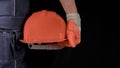 An engineer or handyman holds an orange hard hat. Close-up. Civil Engineering. Place for text. Royalty Free Stock Photo