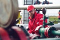 Engineer in hard-hat. Face behind pipeline machinery, fuel and oil refinery.