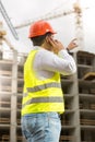 Engineer in hardhat talking by phone and pointing at building si Royalty Free Stock Photo