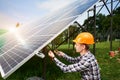 Engineer in helmet connects solar panels on a green plantation. Green ecological power energy generation.