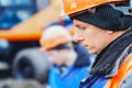 Engineer in helmet looks down. Large portrait on side. Caucasian worker in construction clothing stands close-up outside Royalty Free Stock Photo