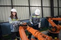 Engineer standing by robotic arm and operating machine in industry factory Royalty Free Stock Photo
