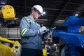 Engineer standing by robotic arm and operating machine in industry factory Royalty Free Stock Photo