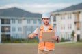 Engineer hold paper board for text. Builder showing signboard placard banner, poster. Builder at construction site