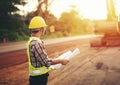 Engineer holding blueprint at road construction site with machinery background Royalty Free Stock Photo