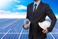 Engineer holding hardhat and blueprint for working at solar energy power plant against beautiful sky with in concept ecology