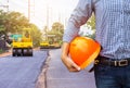 Engineer holding safety helmet at road construction site