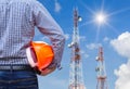 Engineer holding safety helmet with telecommunication tower pillars