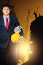 engineer holding yellow helmet for workers security on background of new highrise apartment buildings Royalty Free Stock Photo